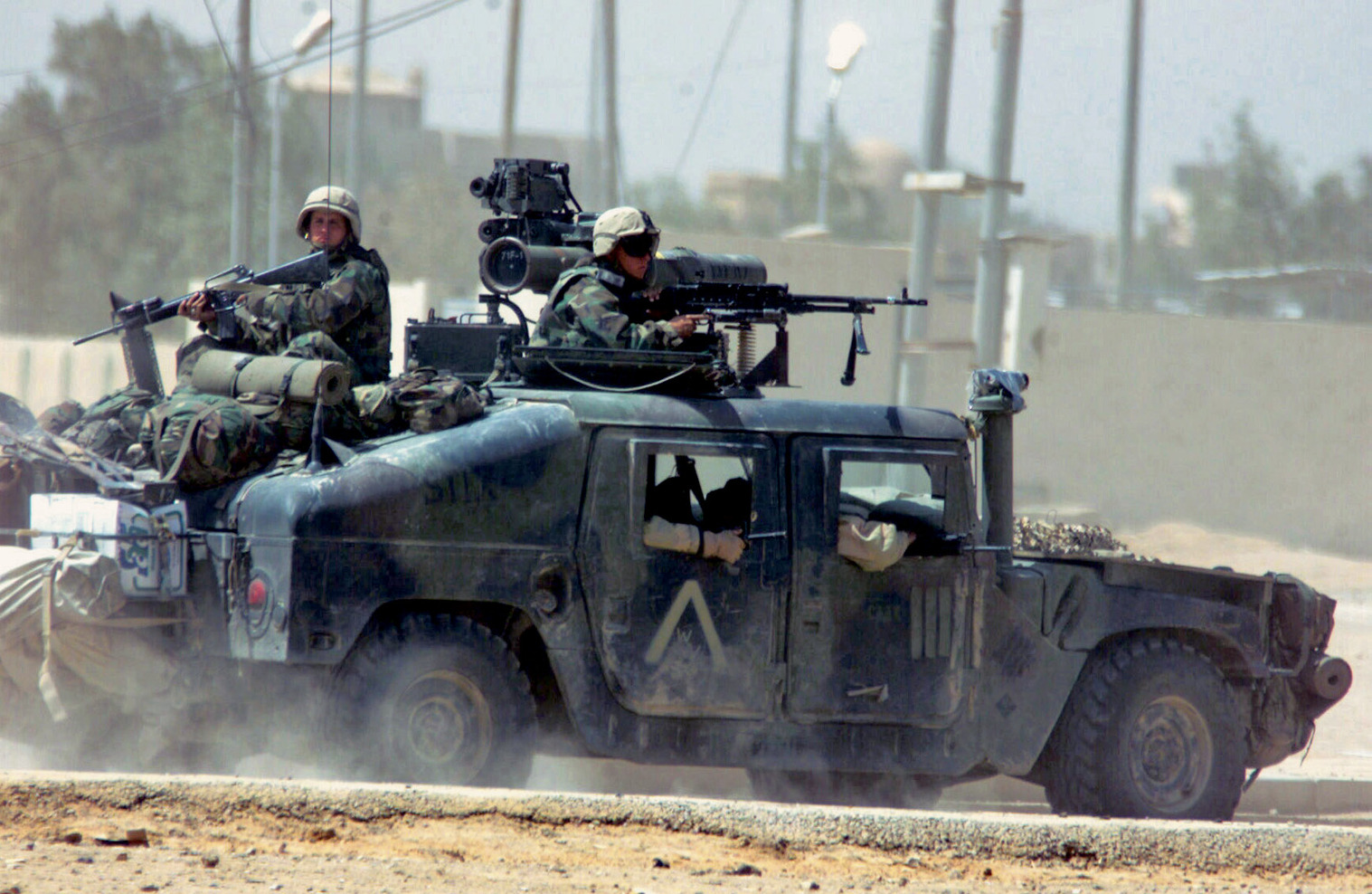 030401-M-5977R-010 Nasiriyah, Iraq (Apr. 1, 2003) -- U.S. Marines from Task Force Tarawa move to support fellow Marines in a High Mobility Multipurpose Wheeled Vehicle (HMMWV) equipped with a 50 cal. heavy machine gun attached to it during a fire-fight in Nasiriyah.  Task Force Tarawa is conducting combat missions in support of Operation Iraqi Freedom, the multi-national coalition effort to liberate the Iraqi people, eliminate Iraq’s weapons of mass destruction, and to end the regime of Saddam Hussein.  U.S. Marine Corps photo by Lance Cpl. Gordon A. Rouse.  (RELEASED) 