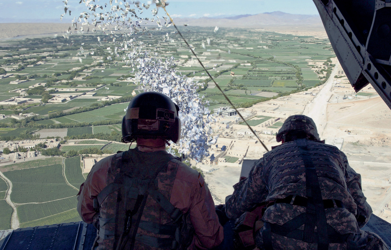 US Army (USA) Reserve (USAR) Sergeant First Class (SFC) Len Tidey (left), Bravo Company (B Co), 7-158th Aviation Battalion (BN), 244th (Theater) Aviation Brigade, watches as SFC Tom Rees (right), 1st Information Operations (IO), 10th Mountain Infantry Division (ID), releases boxes of leaflets in an aerial drop from a USA CH-47 Chinook cargo helicopter over Helmand Province, Afghanistan (AFG), during Operation ENDURING FREEDOM.