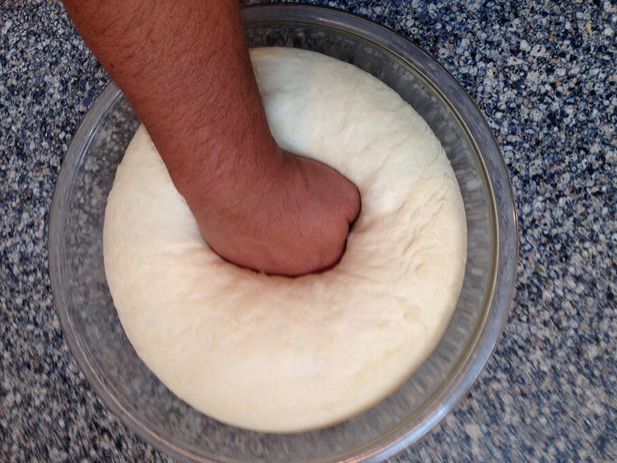 Photo of an arm punching down dough.