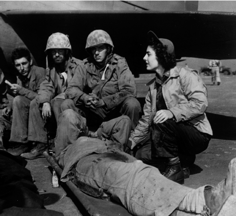 First Navy nurse who saw action on a battlefield, Ens. Jane Kendiegh Cheverton attends a wounded man on Iwo Jima before taking off with casualties on a Navy evacuation plane. Courtesy of NHC