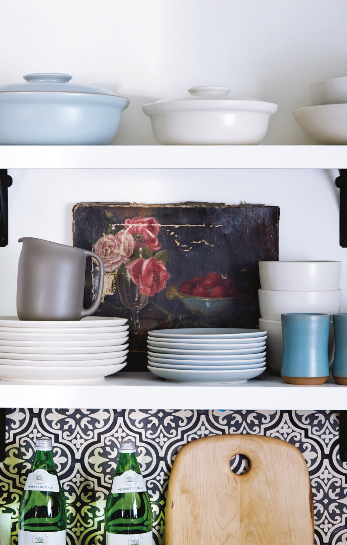 Rather than organizing a blue pot above a stack of blue plates and white above white, we “crisscrossed” the colors between shelves so that your eye moves diagonally across the photo and not just up and down. The art turns ordinary stacks of plates into a stylish vignette.