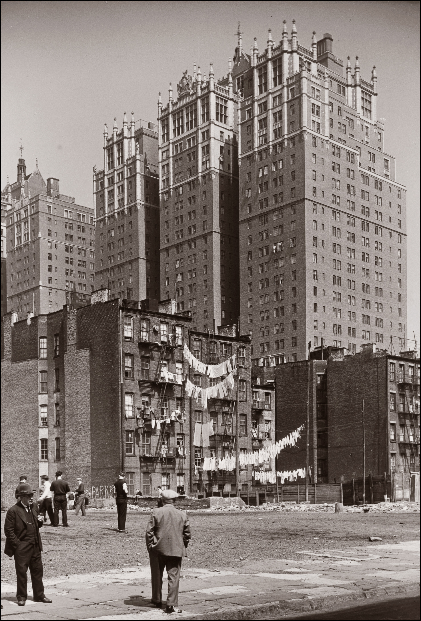 View of Tudor City. Tenement buildings with hanging laundry on clotheslines are in the middle- ground. A few men are scattered in the foreground (left).