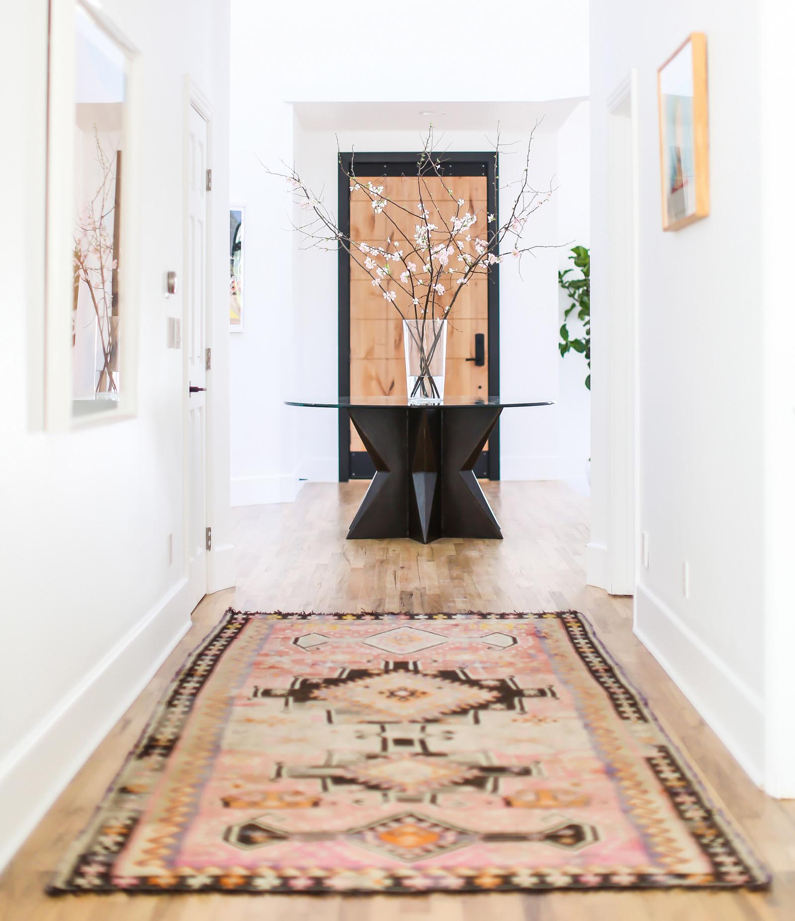 Pink, red and salmon dyes integrated with stark black patterns and borders of this large runner provide exciting contrast to the hallway’s clean palate and light hardwood flooring.