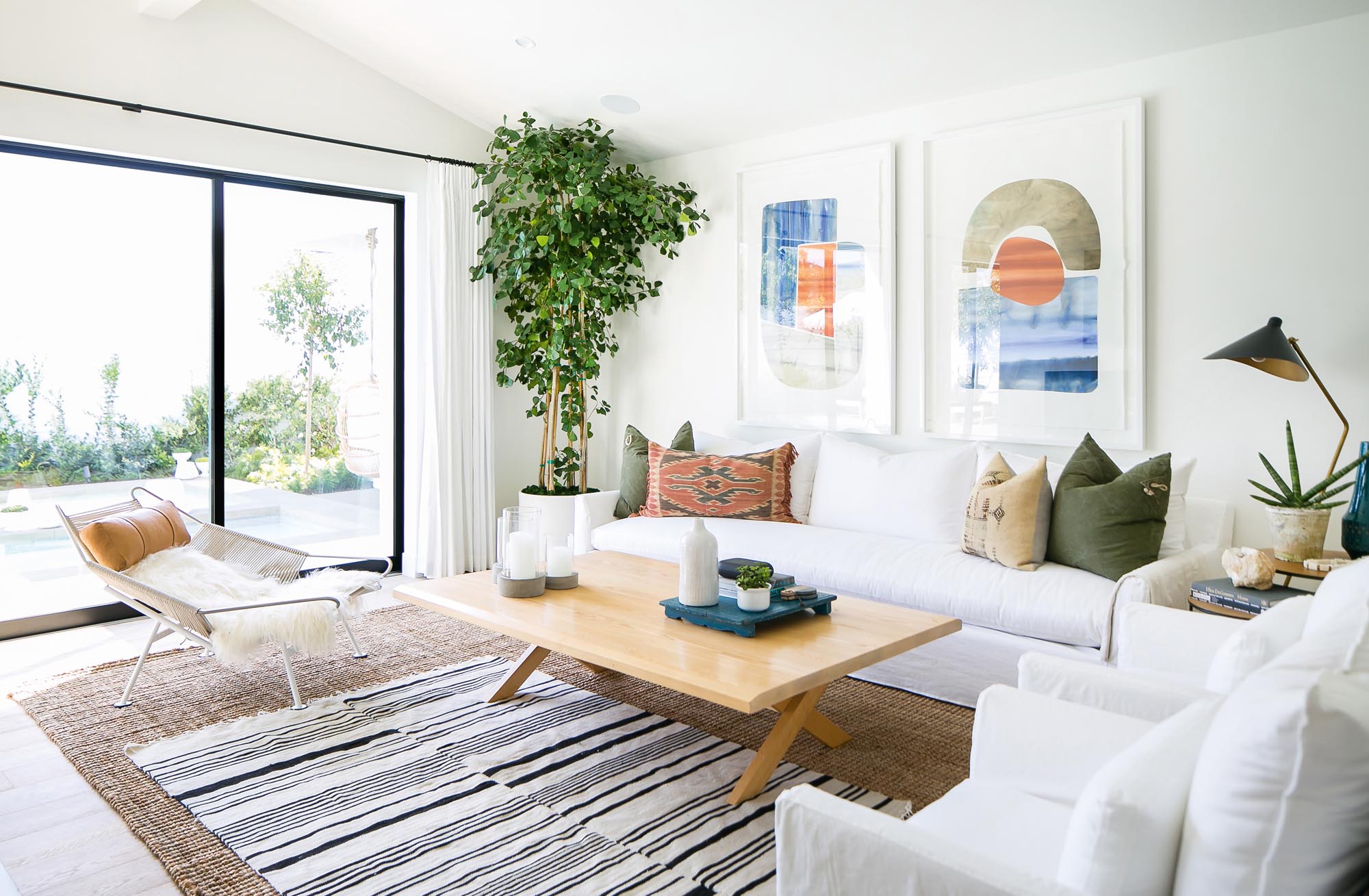 Photo of living room with white furnishings, neutral rugs, and contemporary art.