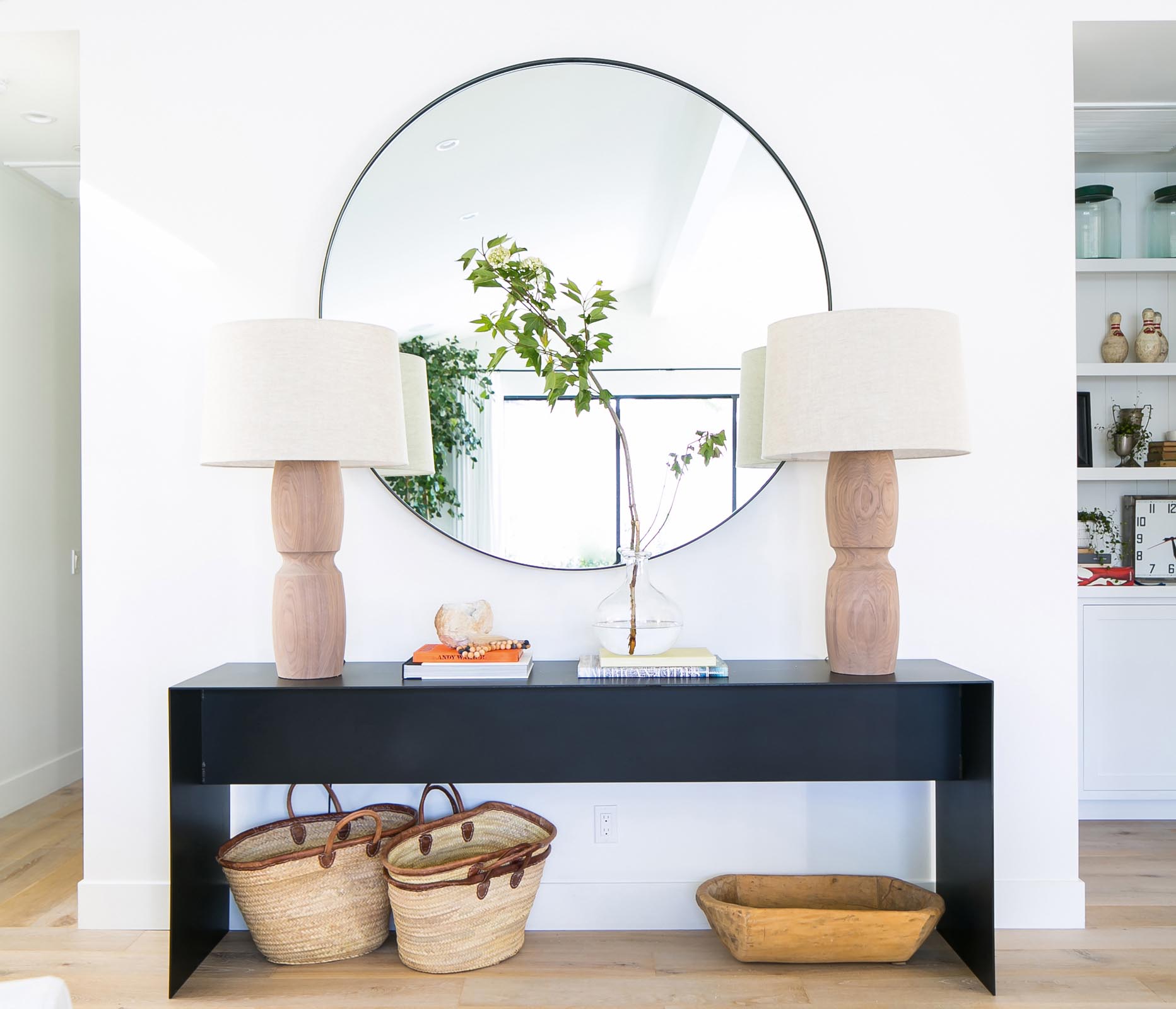 Photo of a black table against a white wall and large mirror.