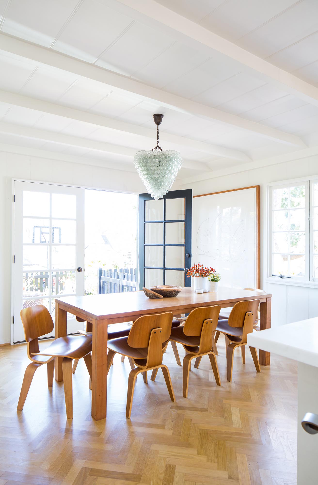 The open-air dining area plays host to a large dining table complete with contemporary wood chairs that play off the beautiful chevron-shaped French oak hardwood floors.