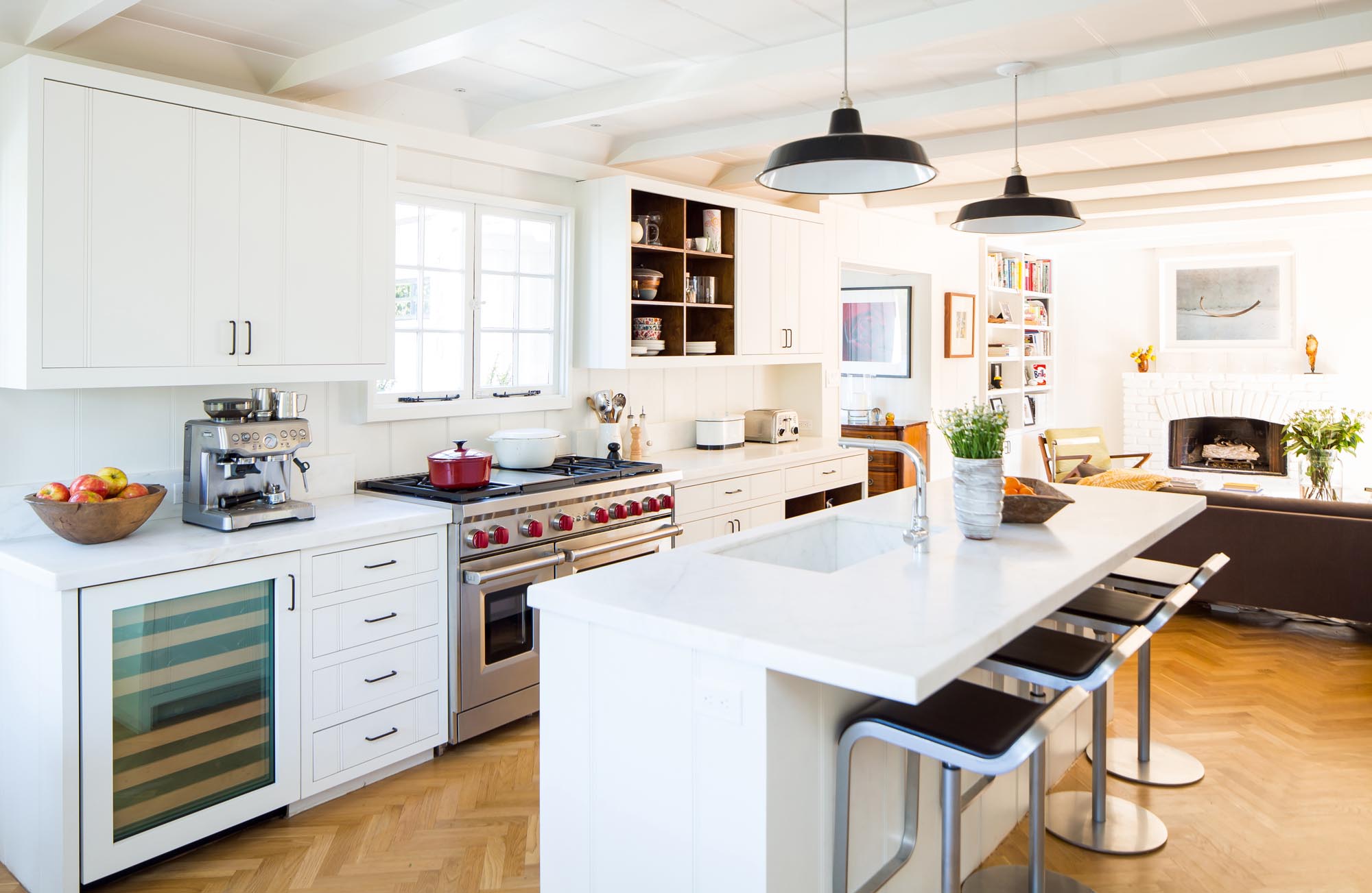 The open-air kitchen and sitting area are complemented by a contemporary island and sleek steel chairs for additional seating.