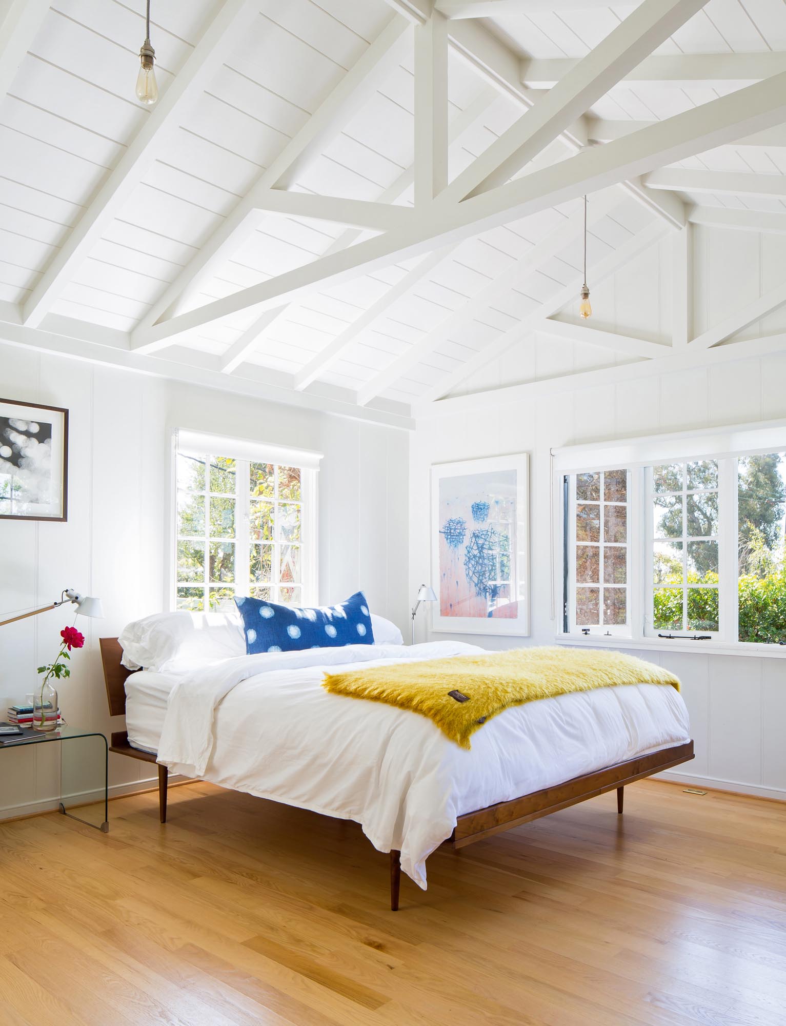 Photo of an airy bedroom with white-painted timbered ceiling.