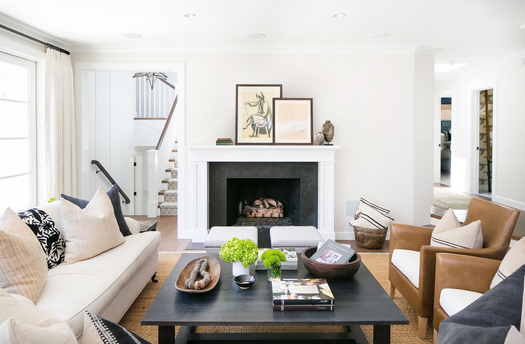 Photo of a living area in neutrals with framed sketches on the hearth.