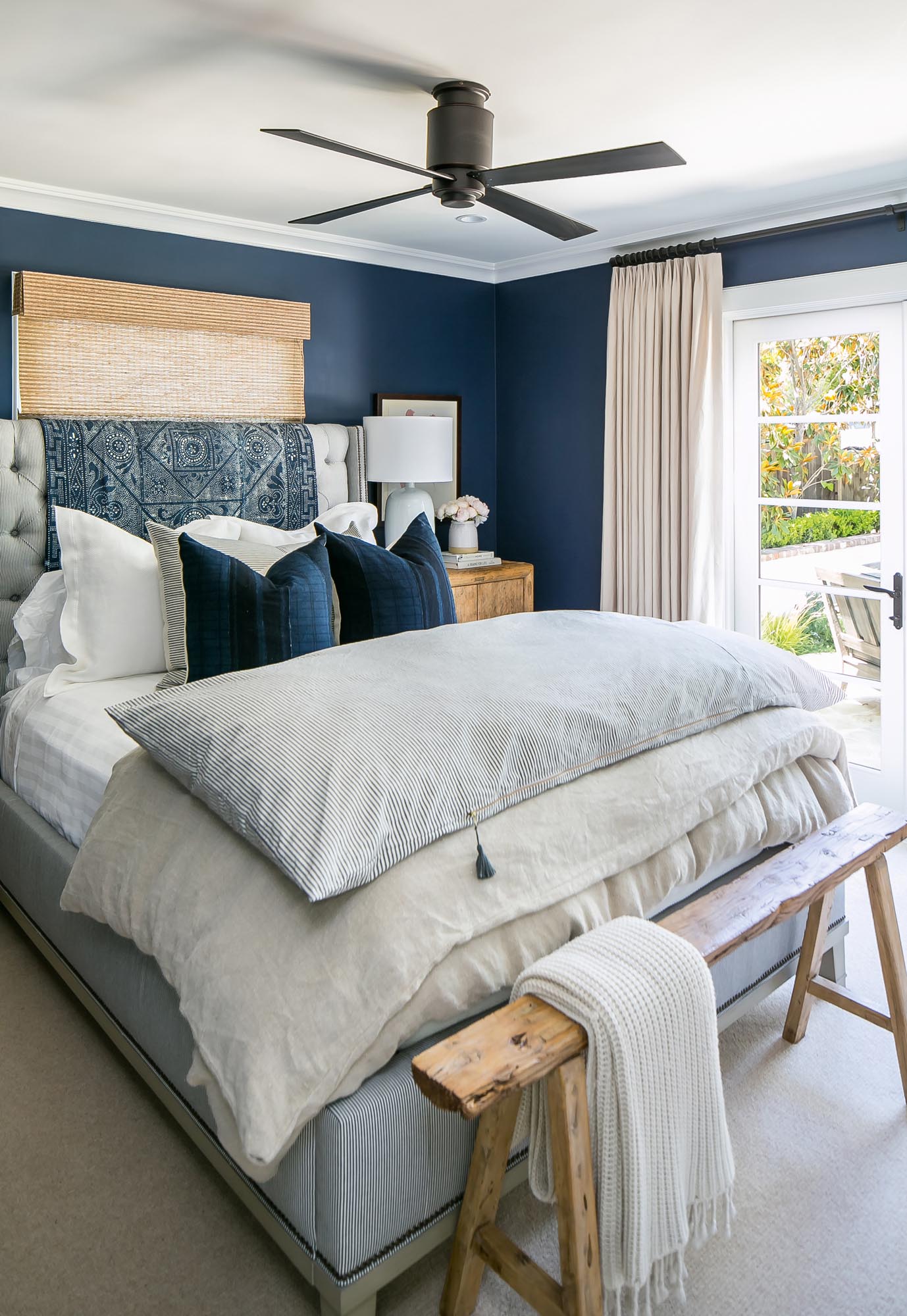 Photo of a bed with dark blue pillows that match the walls.