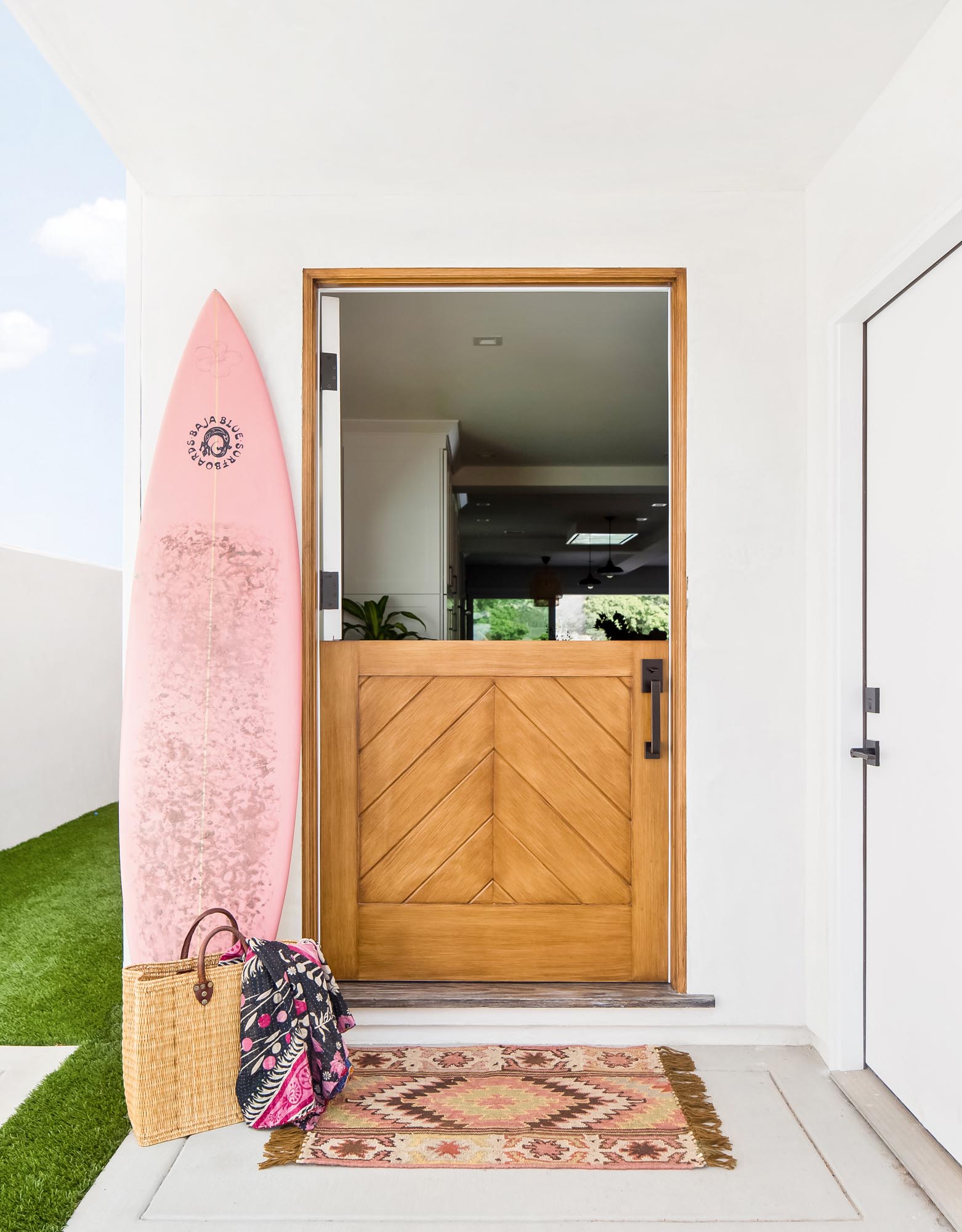 Photo of entryway with a surfboard beside a chevron-patterned door.