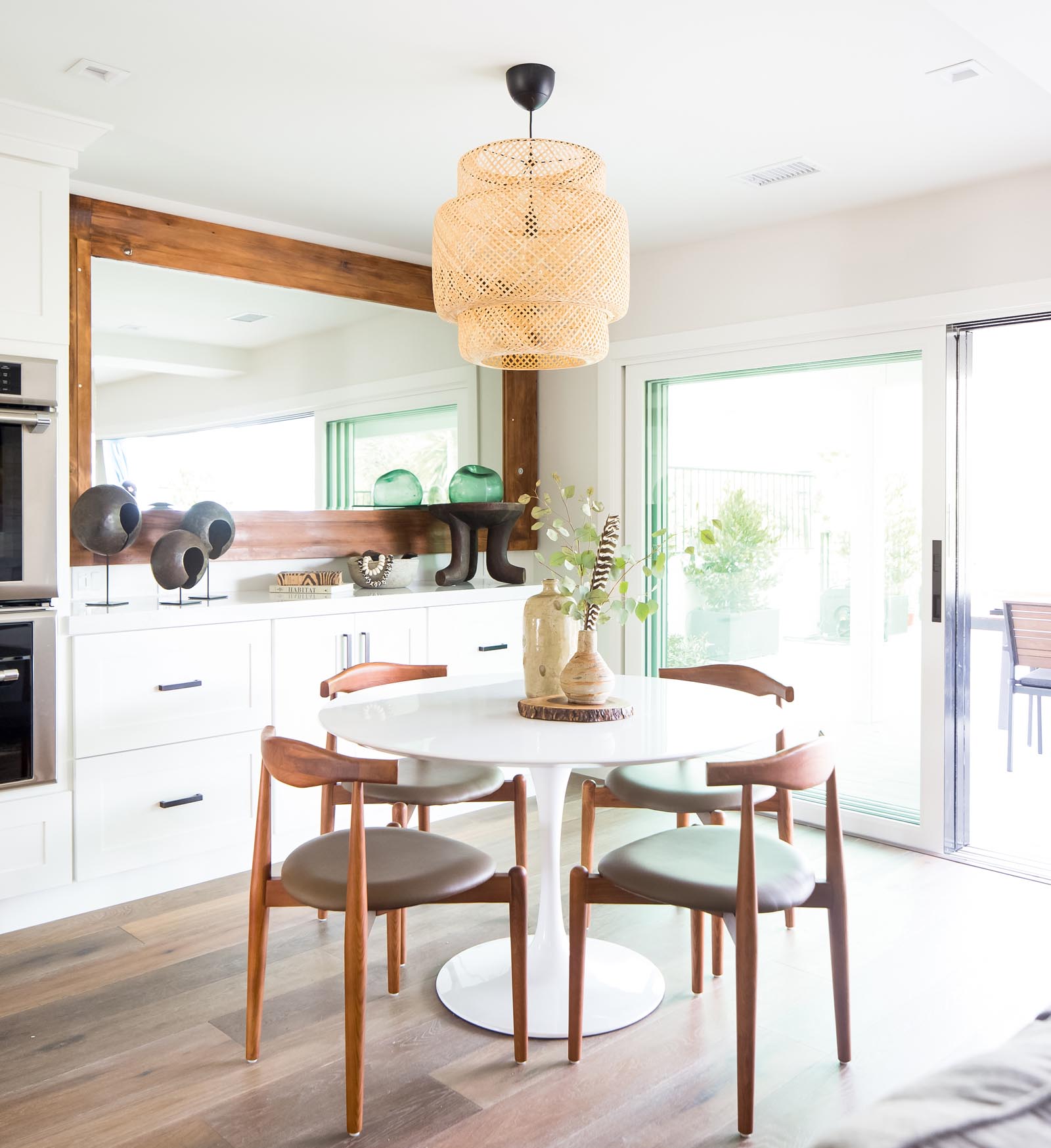 Photo of the dining area with a mirror and sculptures topping a built-in white sideboard.