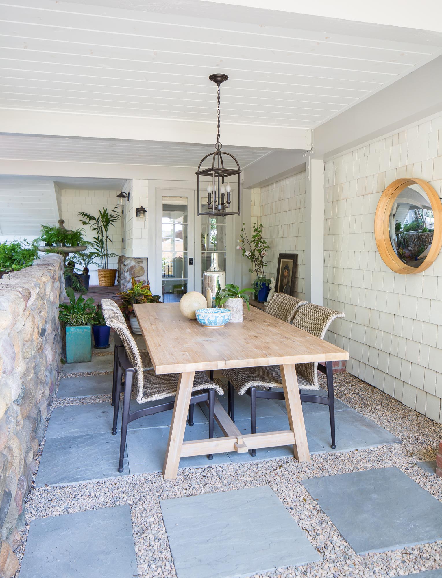 Photo of a dining area on flagstones outside by potted plants.