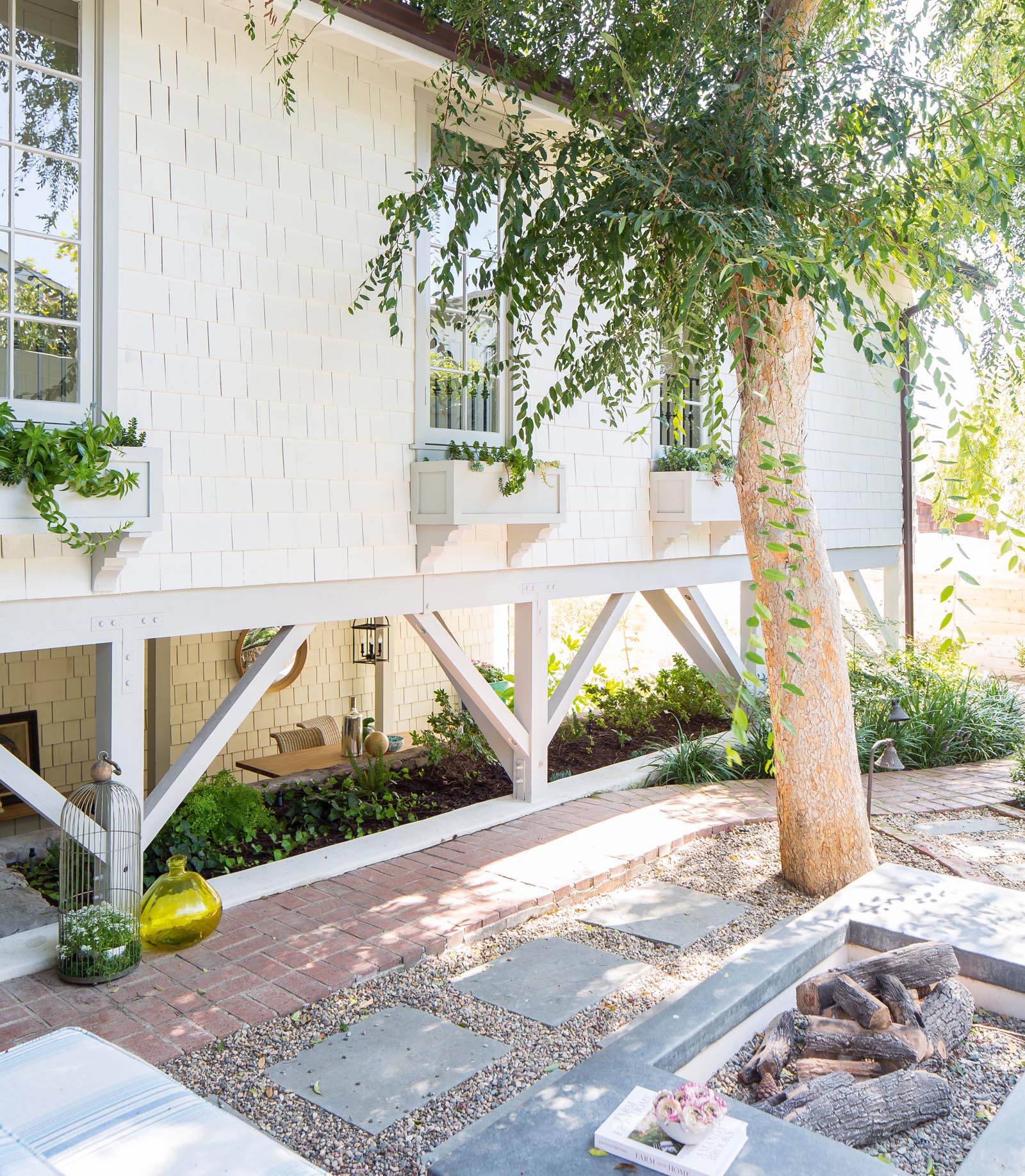 Photo of a firepit outside narrow windows with flower boxes.