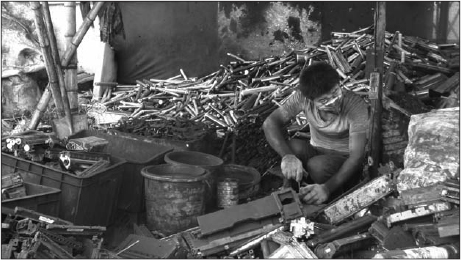 Worker dismantling toner cartridges, covered with toner, in Guiyu, China