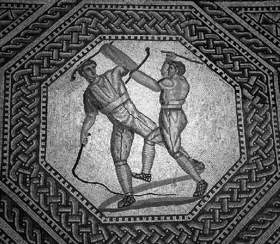 Due paegniarii, cioè due gladiatori per burla, simulano i combattimenti a colpi di bastoni e frusta, e rappresentano un intrattenimento divertente tra un combattimento e l’altro. Da uno dei mosaici perfettamente conservati nella villa romanica di Nennig, in Germania (Römische Villa Nennig).