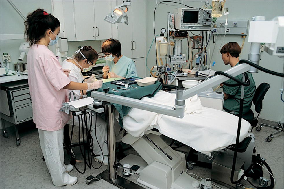 Photo displaying a group of people performing dental treatment on a patient under general anesthesia, using comprehensive equipments.