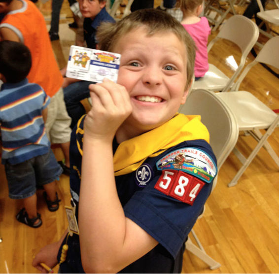 image of Stephen in a boyscout uniform smiling and holding up a card