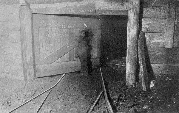 "I 'AIN'T SEEN DAYLIGHT FOR TWO YEARS." Trapper boy working a twelve-hour day below ground, often too tired to go up in the cage at the end of the day and sleeping on the ground beside the track. (Courtesy of the Ridgway Co.)