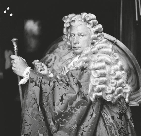 Carlos de Beistegui, host of the Venetian Ball at the historic Palazzo Labia, looking into the camera and dressed in costume as the Procurator of Venice with a silk damask robe and curled wig. (Photo by Cecil Beaton/Condé Nast via Getty Images)