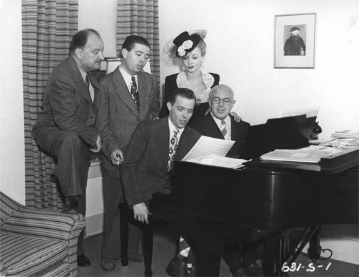 FIGURE 11.2. Lyricist Harold Adamson stands between a studio executive and movie actress Carole Landis; composer Jimmy McHugh (right) sits next to crooner Dick Haymes. Courtesy of Photofest.