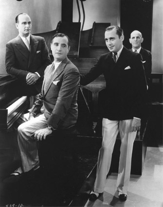 FIGURE 9.1 Jack Benny (center) checks out composer Fred Ahlert (at piano) and lyricist Roy Turk, while composer Fred Fisher watches from behind. Courtesy of Photofest.