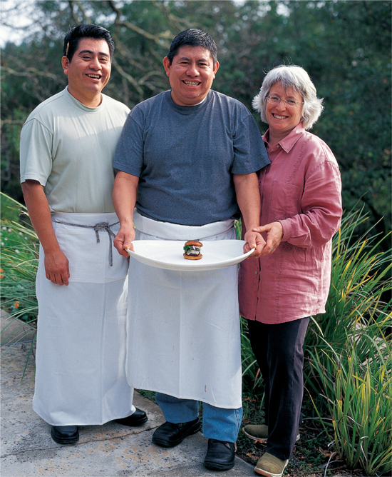 Cindy and the two men holding a huge white platter outside, upon which sits a single, crafted tiny hamburger