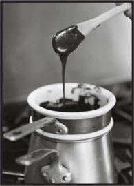 Making chocolate sauce and an older woman offering a spoon from a glass to a younger