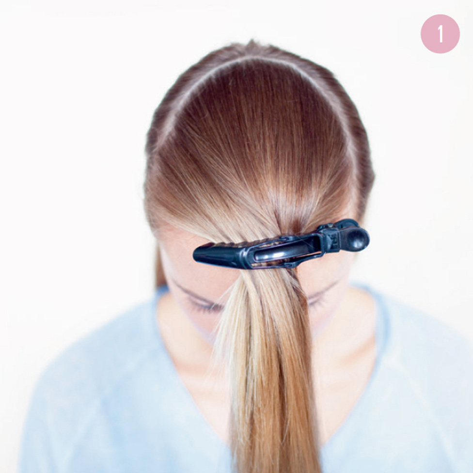 1 Separate out half your hair at the top into a half-moon and secure with the alligator clip. Then brush the hair at the back