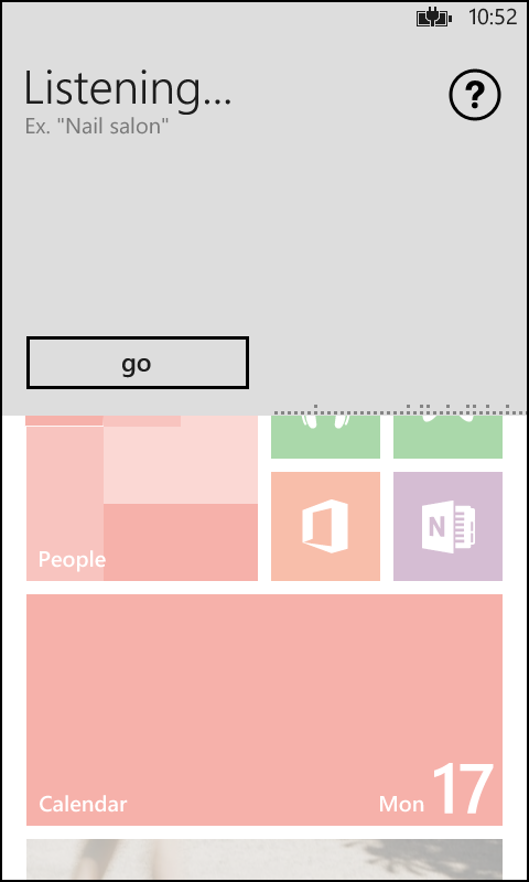 A screenshot of the Global Search Experience (GSE) overlaid on the Windows Phone Start screen. The GSE covers half of the screen and is shown as listening for input.