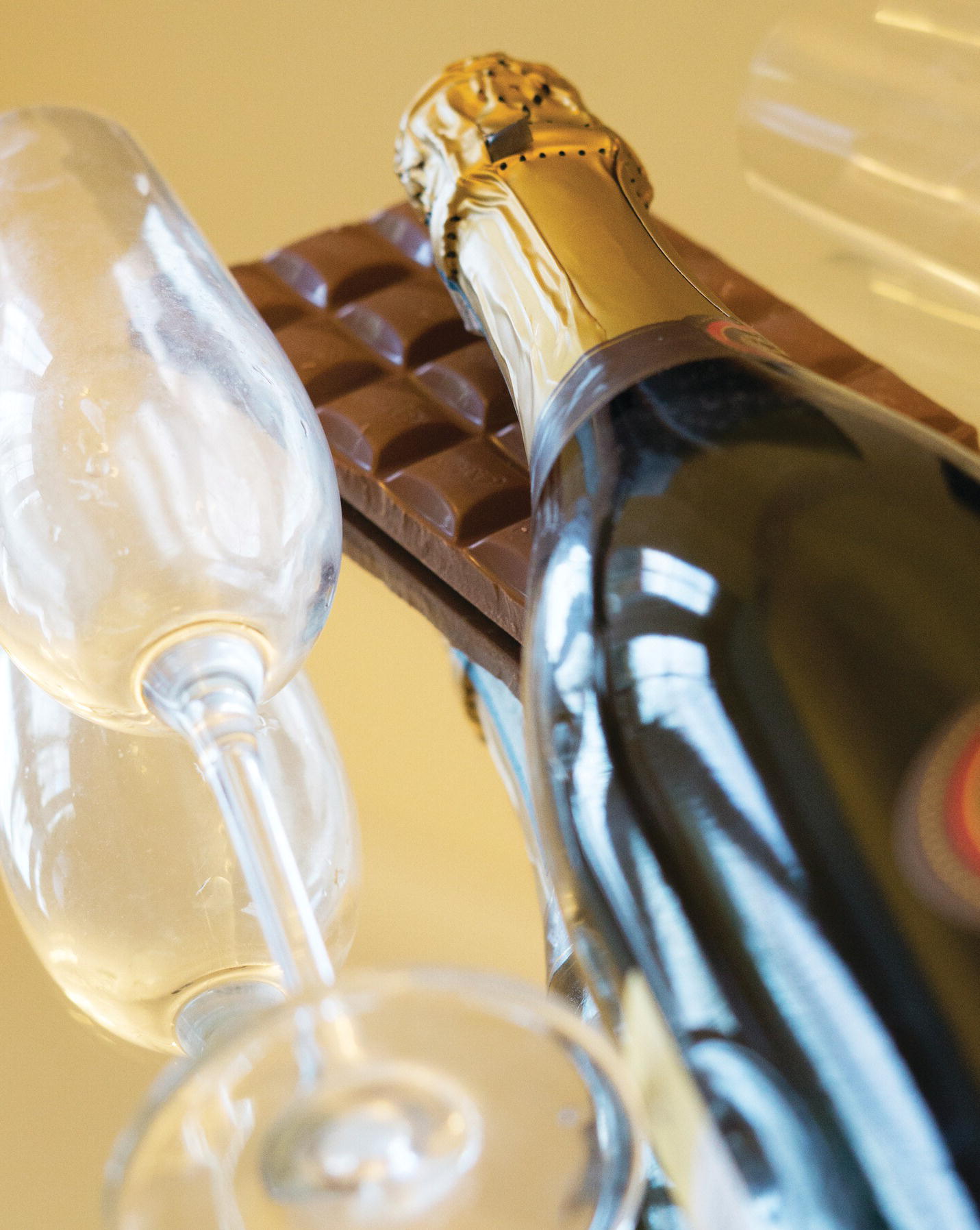 Photo displaying a wine glass, a bottle of wine, and a bar of chocolate.