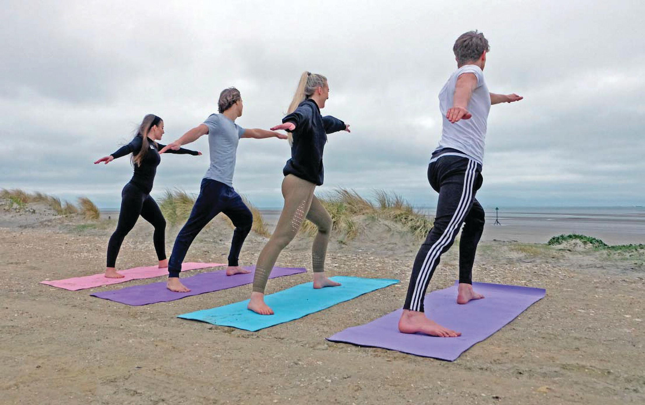 Photo of two men and two women doing yoga.