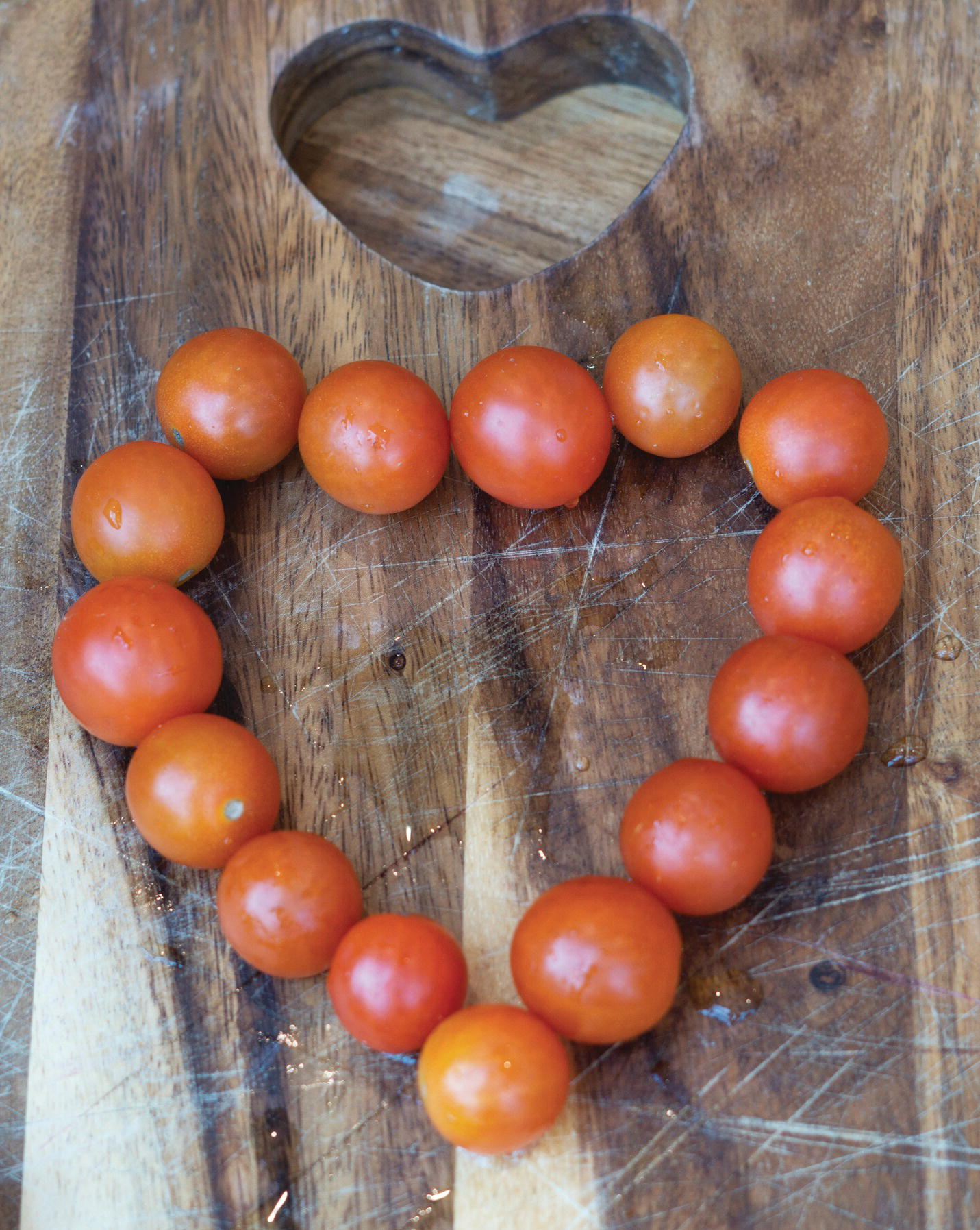 Photo displaying 15 cherry tomatoes arranged in a heart-shaped formation.