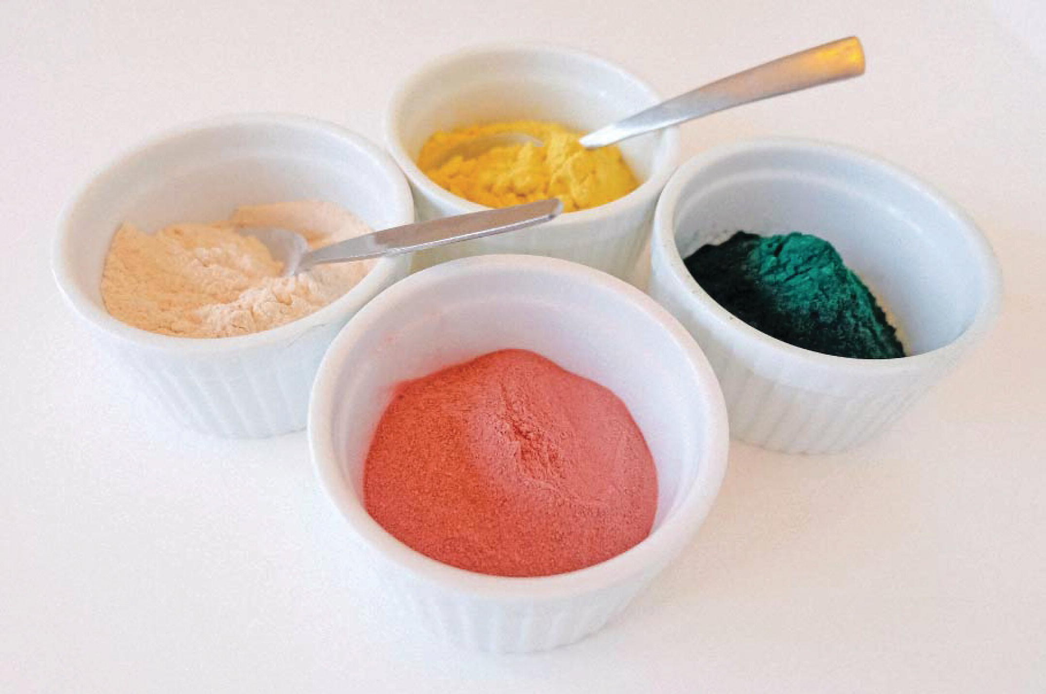 Photo displaying four bowls containing various powder such as spirulina, baobab, and pine pollen.