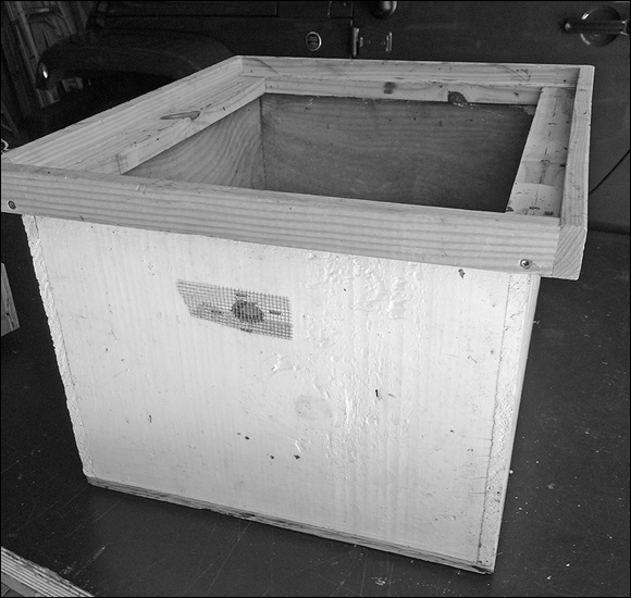 Photograph of a covered box or container that makes it easy to protect and transport the comb hanging vertically from a top bar hive.