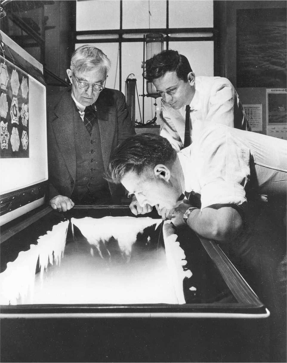 Irving Langmuir (left) and Bernard Vonnegut (right) watch as Vincent Schaefer huffs into a freezer to create ice crystals, a precursor step to making artificial rain. (Photo courtesy miSci-Museum of Innovation and Science)