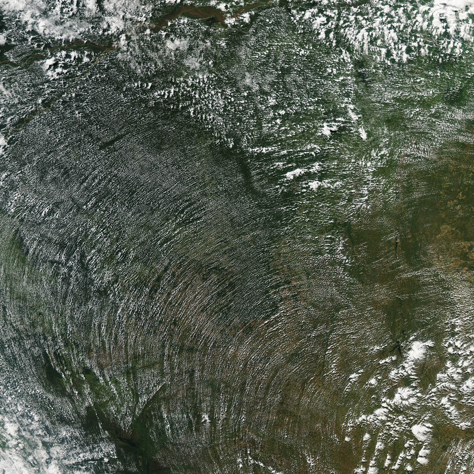 To the human eye, the wind is invisible. It can only be visualized by proxy, by its expressions in other phenomena like blowing leaves, airborne dust, white-capped waters—or the patterns of clouds. Acquired in June 2014 by the Aqua satellite, this image shows a broad swath of the Amazon rainforest in Brazil and Bolivia as it appeared in the early afternoon. As sunlight warms the forest in the morning, water vapor rises on columns of heated air. When that humid air runs into a cooler, more stable air mass above, it condenses into fluffy cumulus clouds.  Cumulus cloud streets often trace the direction, and sometimes the intensity, of winds—lining up parallel to the direction of the wind. Usually this means a straight line, but clouds can also line up along the concentric, curved lines of high-pressure weather systems, as they did here. 