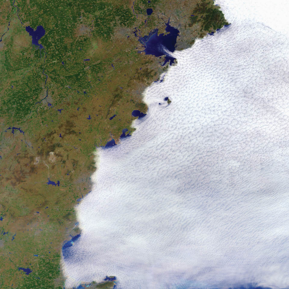 The ocean does not heat up as much throughout a day as landmasses do. For this reason, cool, moist marine air commonly gives rise to dense clouds over the ocean.  In this example from the coast of China, an onshore wind carries the clouds from the ocean toward the land. But the land is warmer, drier, and unfavorable for cloud growth. As a result, the marine clouds that move onshore tend to evaporate, leaving a cloud layer that traces the coastline.