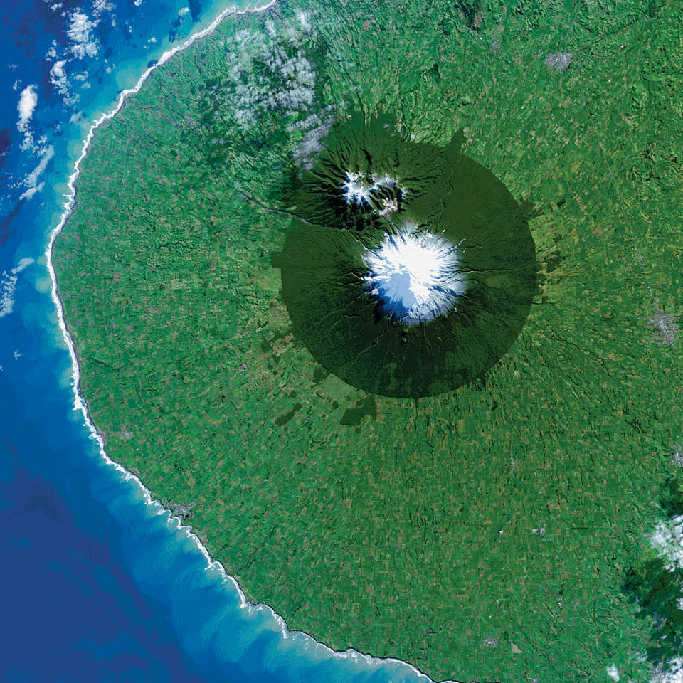 The circular pattern of New Zealand’s Egmont National Park stands out from space as a human fingerprint on the landscape.  The park protects the forested and snow-capped slopes around Mount Taranaki (Mount Egmont to British settlers). It was established in 1900, when officials drew a radius of 10 kilometers around the volcanic peak. The colors differentiate the protected forest (dark green) from once-forested pasturelands (light- and brown-green). Landsat 8 acquired this image of Taranaki and the  park in July 2014.