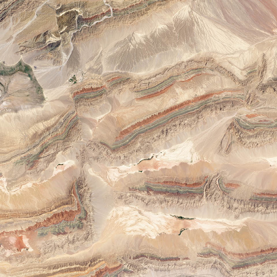 Just south of the Tien Shan mountains, in northwestern Xinjiang province, a remarkable series of ridges dominates the landscape. The hills are decorated with distinctive red, green, and cream-colored sedimentary rock layers. The colors reflect rocks that formed at different times and in different environments. Landsat 8 captured this image of the Keping Shan thrust belt in July 2013.