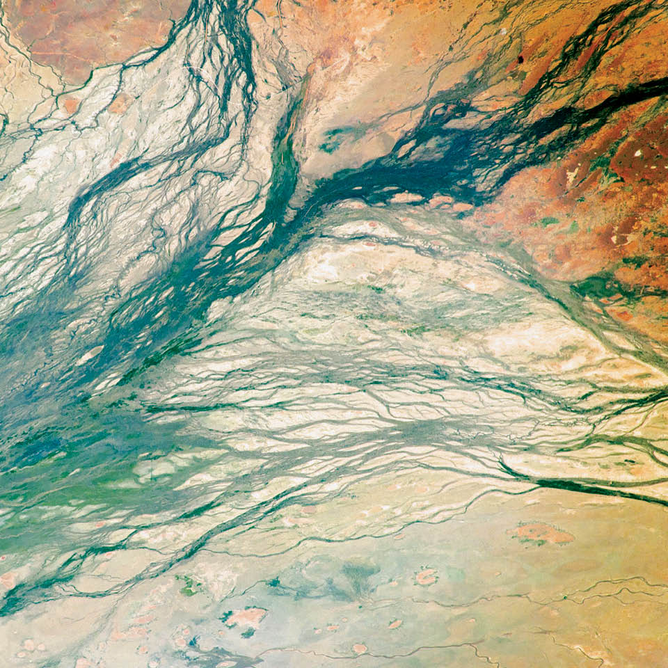 Australia’s Channel Country is full of hundreds of channels, as the Georgina, Burke, and Hamilton rivers merge into the very broad floodplain of Eyre Creek. The land is flat and the drainage is poor, which encourages semi-permanent wetlands to form at the meeting points of the rivers. Every few decades, the floodplain carries extremely high discharges of water. For instance, tropical storms to the north can lead to great water flows that inundate the entire width of the floodplain. On such occasions, the floodplain appears as series of brown and green water surfaces with only tree tops indicating the location of the islands. Such is the case in this image taken from the International Space Station in September 2016.