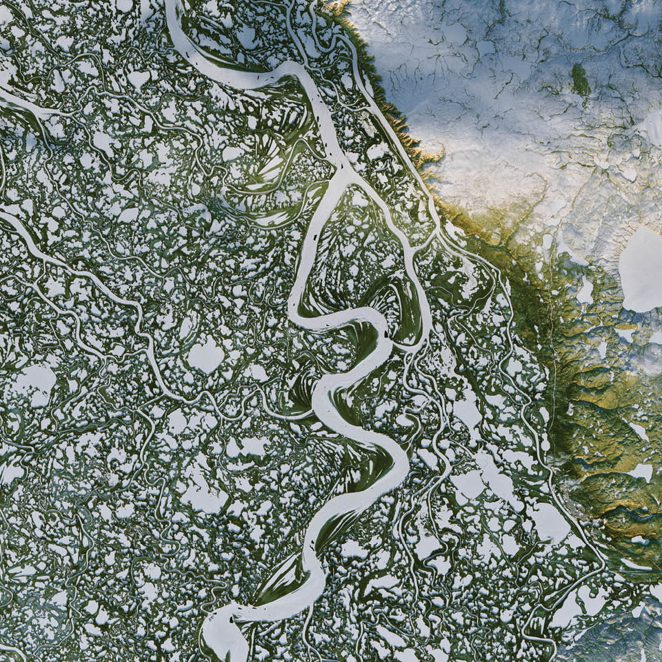 In the Mackenzie River Delta of far northern Canada, snow- and ice-covered waterways stand out amid green, pine-covered land. Those frozen tributaries also become ice roads for trucks carrying supplies between the remote outposts of Inuvik and Tuktoyaktuk. 