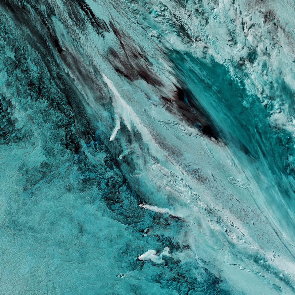 The uninhabited South Sandwich Islands include several active stratovolcanoes. Due to their remote location, these volcanoes  are some of the least studied in the world, though satellites often catch them erupting.  The combination of clouds and ice at these latitudes can make it difficult to see plumes of volcanic ash in natural-color imagery. But using portions of the electromagnetic spectrum that are typically invisible to the naked eye (such as infrared) enables satellites to distinguish ice from ash and clouds. The Aqua satellite captured this false-color image in September 2016. Note the three bright white plumes running down the middle third of the page; they are warmer and brighter in infrared than the cooler ice clouds (teal) around them.