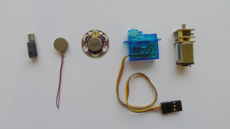 Small motors well suited for wearable applications (left to right: vibration motor (exposed), vibration motor (enclosed), LilyPad vibe board, microservo, and a small gearhead motor)