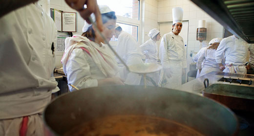 A student at Le Ferrandi culinary school in Paris tends to a simmering pot of veal stock under the watchful eye of his professor.