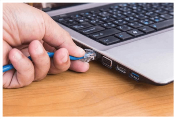 An ethernet cable is plugged into the RJ45 port of a laptop.