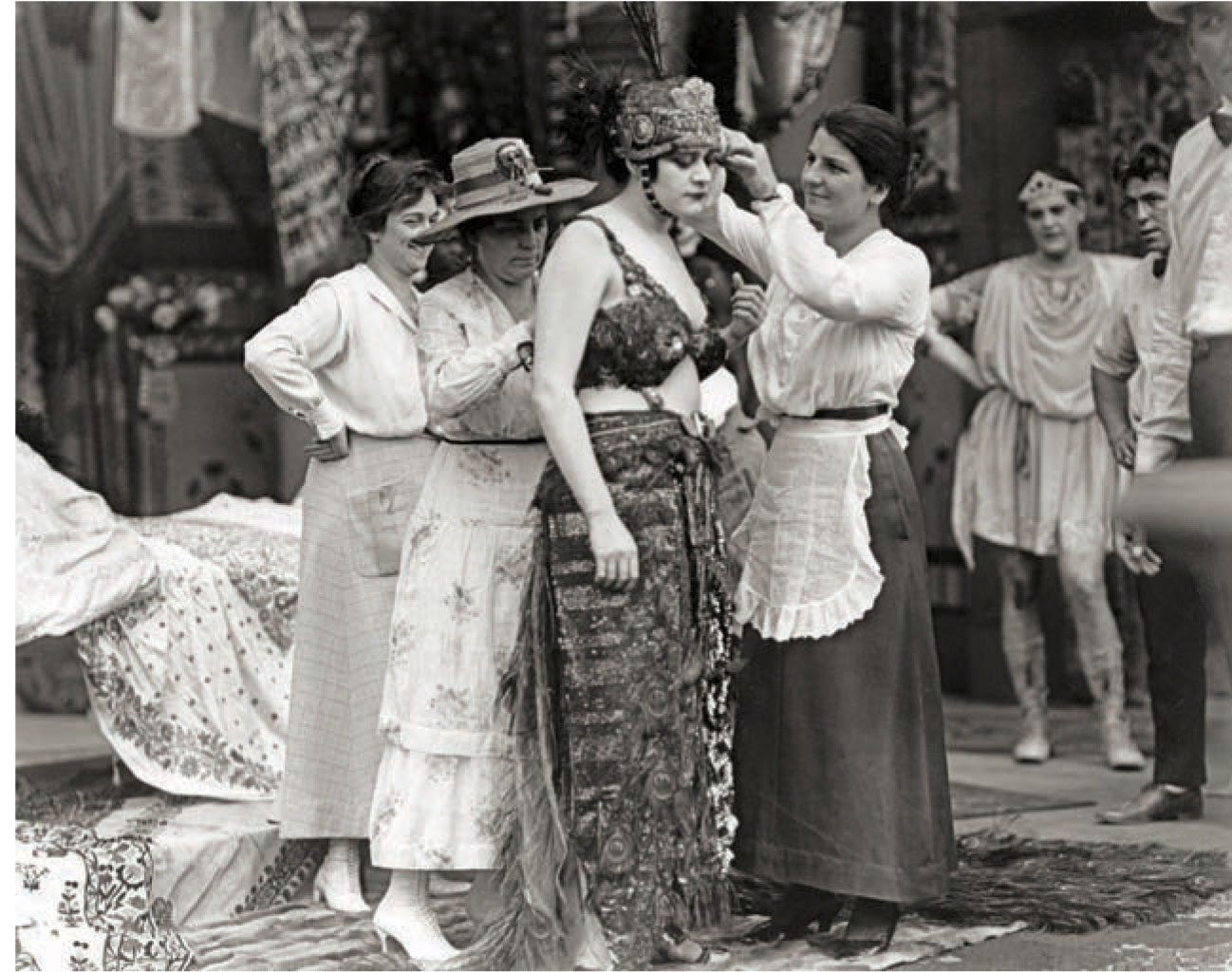 On the set of Cleopatra (1917), Theda Bara’s revealing costume stands in stark contrast to the modest clothing worn by wardrobe personnel.