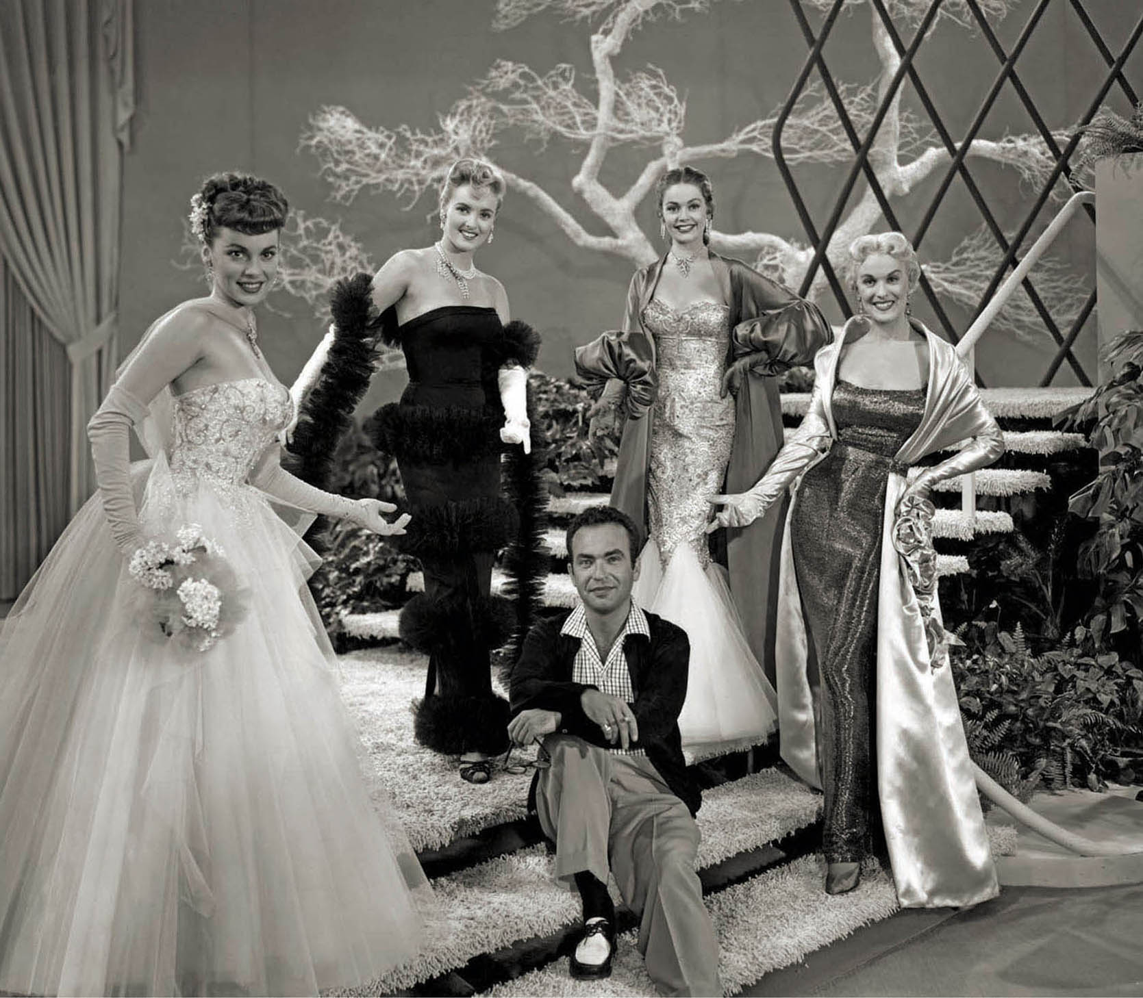 Costume designer Michael Woulfe with models wearing gowns from The French Line (1954).