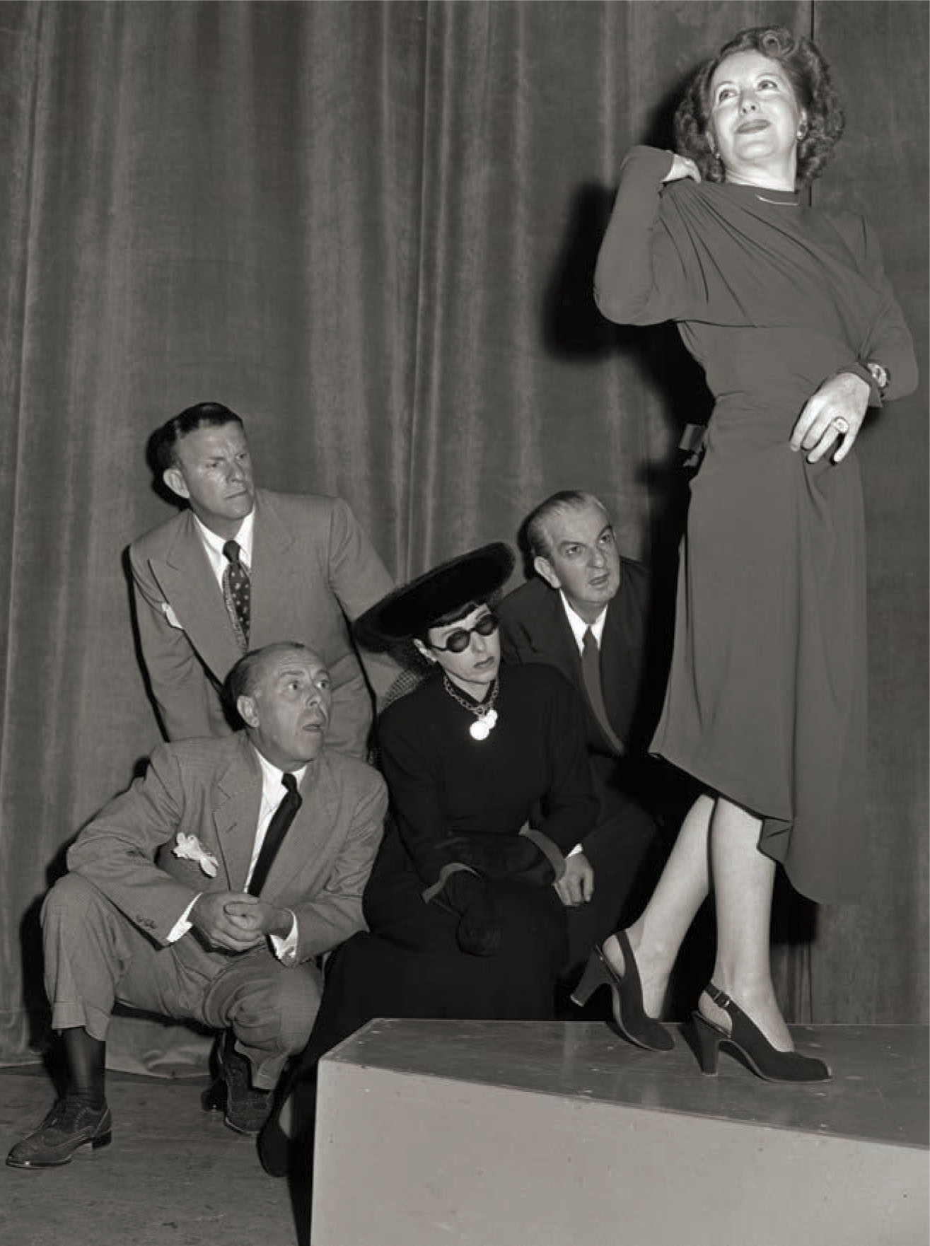 With George Burns behind them, costume designers Howard Greer, Edith Head, and Orry-Kelly discuss the length of the skirt Gracie Allen wears while recording a segment of the Maxwell House Coffee Time Starring Burns and Allen radio program in 1947.