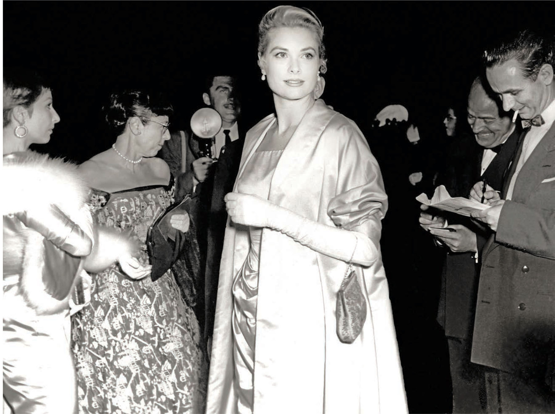 Grace Kelly arrives at the 1955 Oscar ceremony wearing an Edith Head ensemble. Edith can be seen in the background.